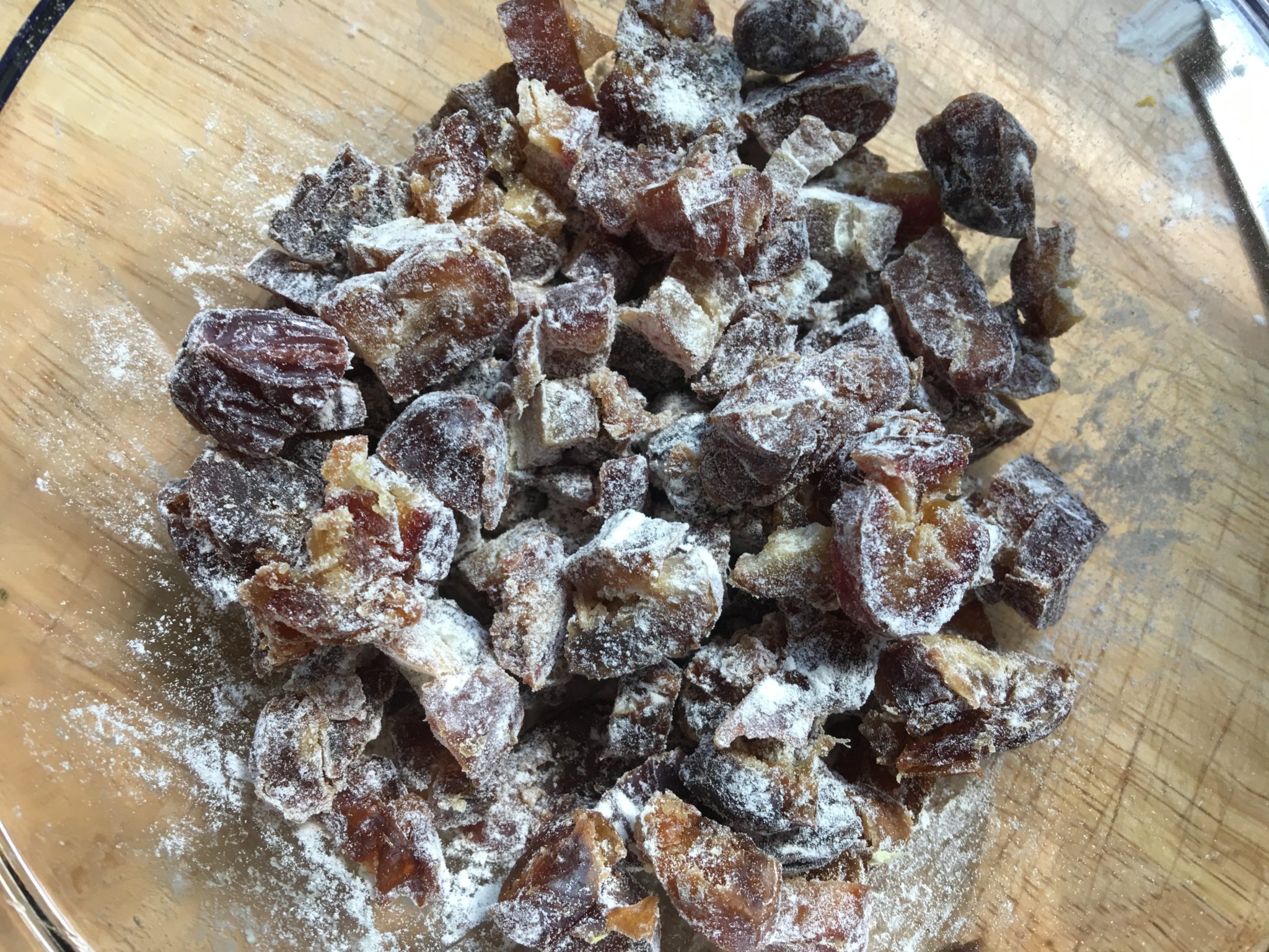 A glass bowl of dates tossed in flour