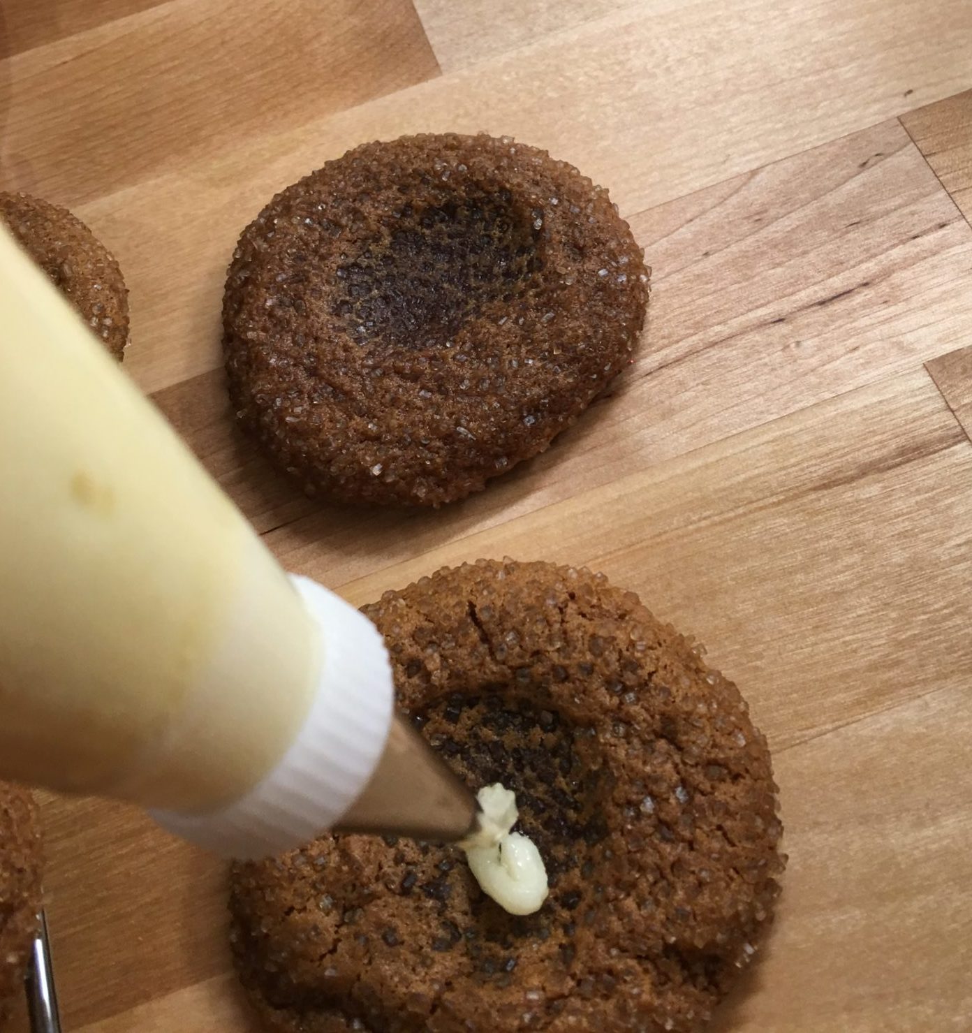 Piping icing into a thumbprint cookie