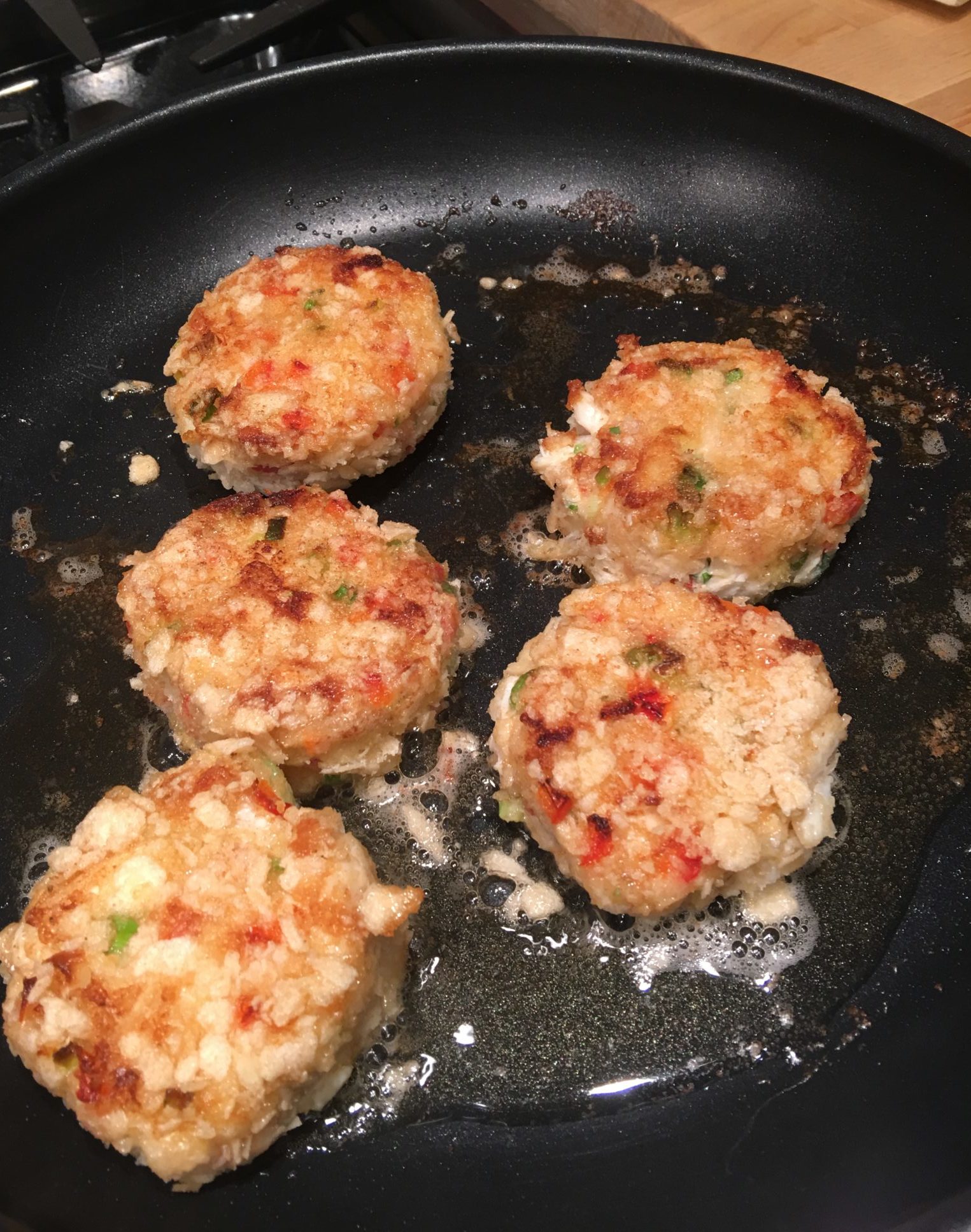 Crab cakes browning in a pan