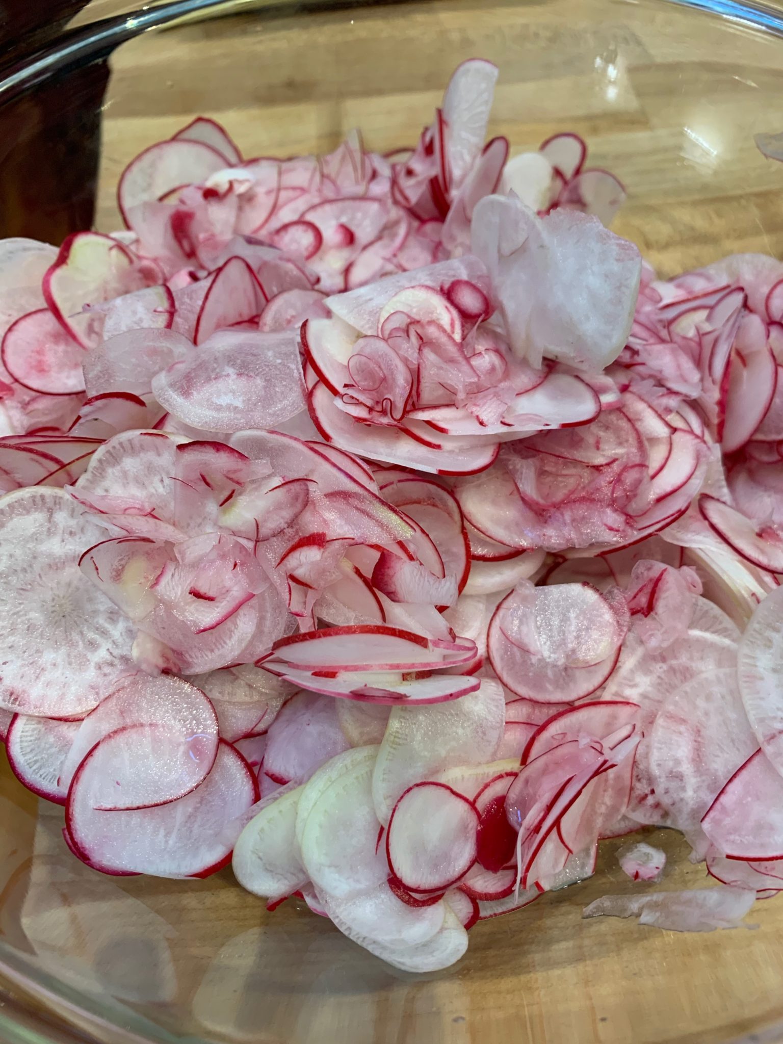 Thin sliced radishes in a glass bowl