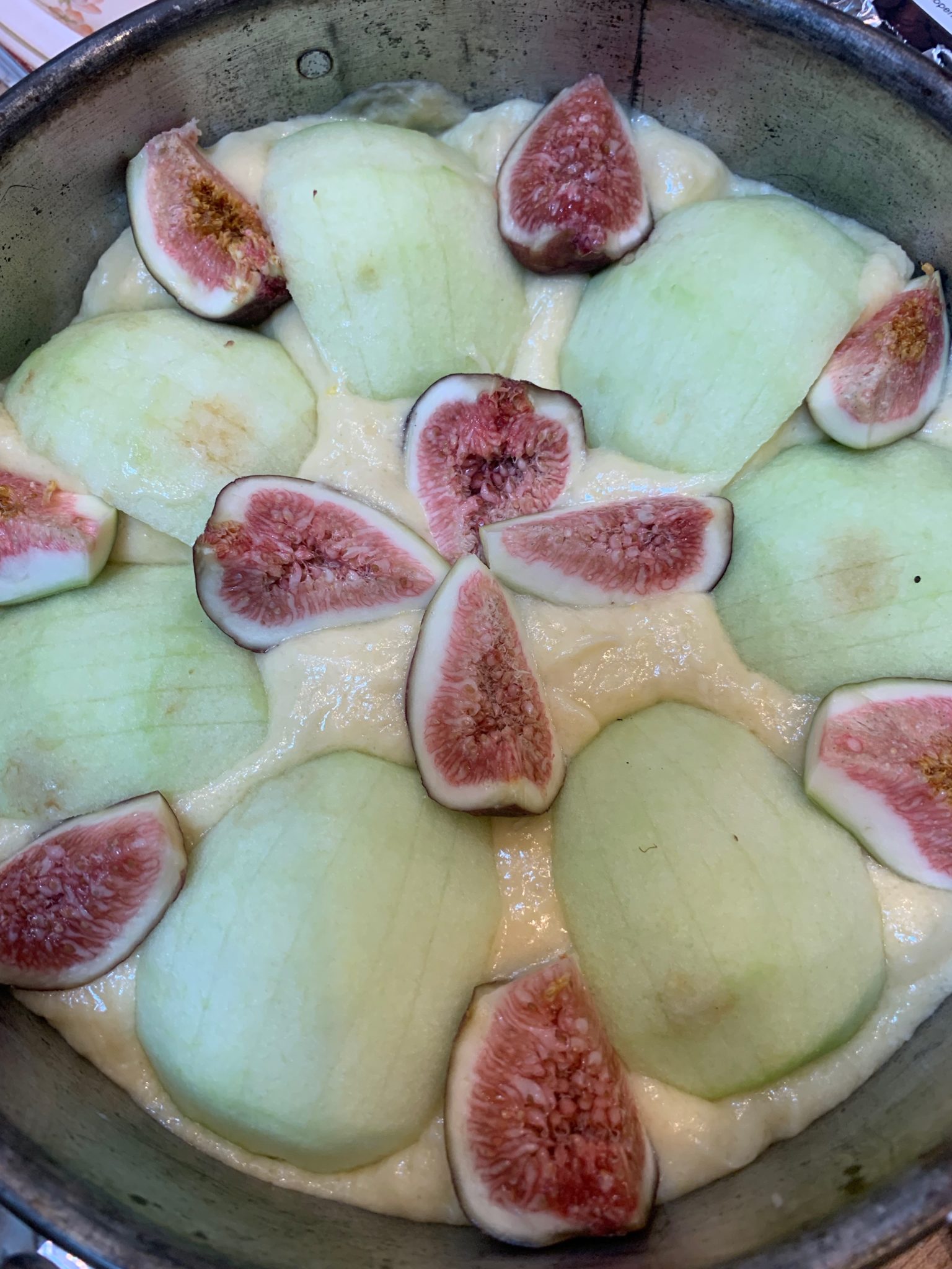 Apples and figs arranged on top of a yellow cake batter