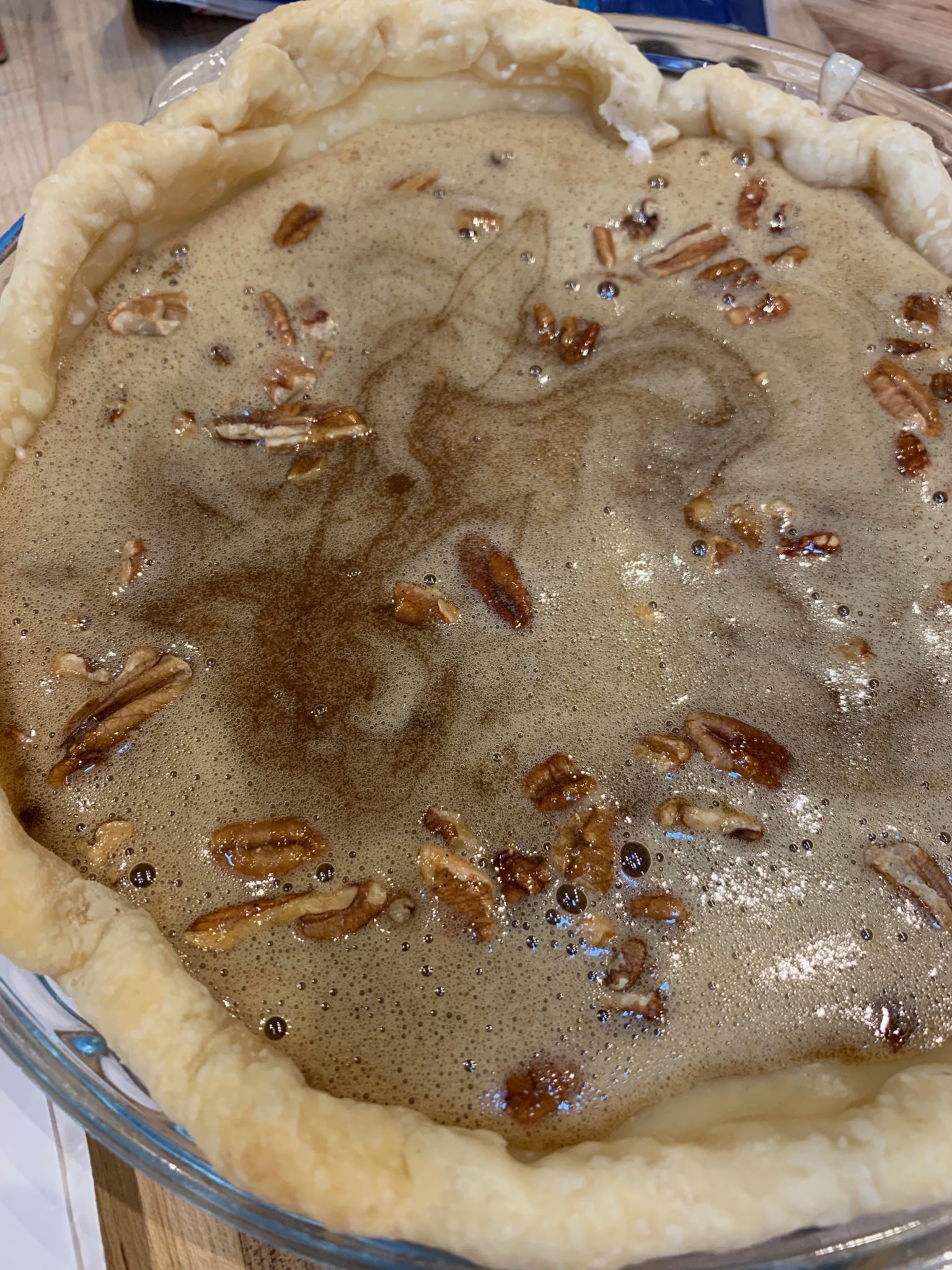showing the pecan pie filling on top of the chopped pecans and cheesecake filling
