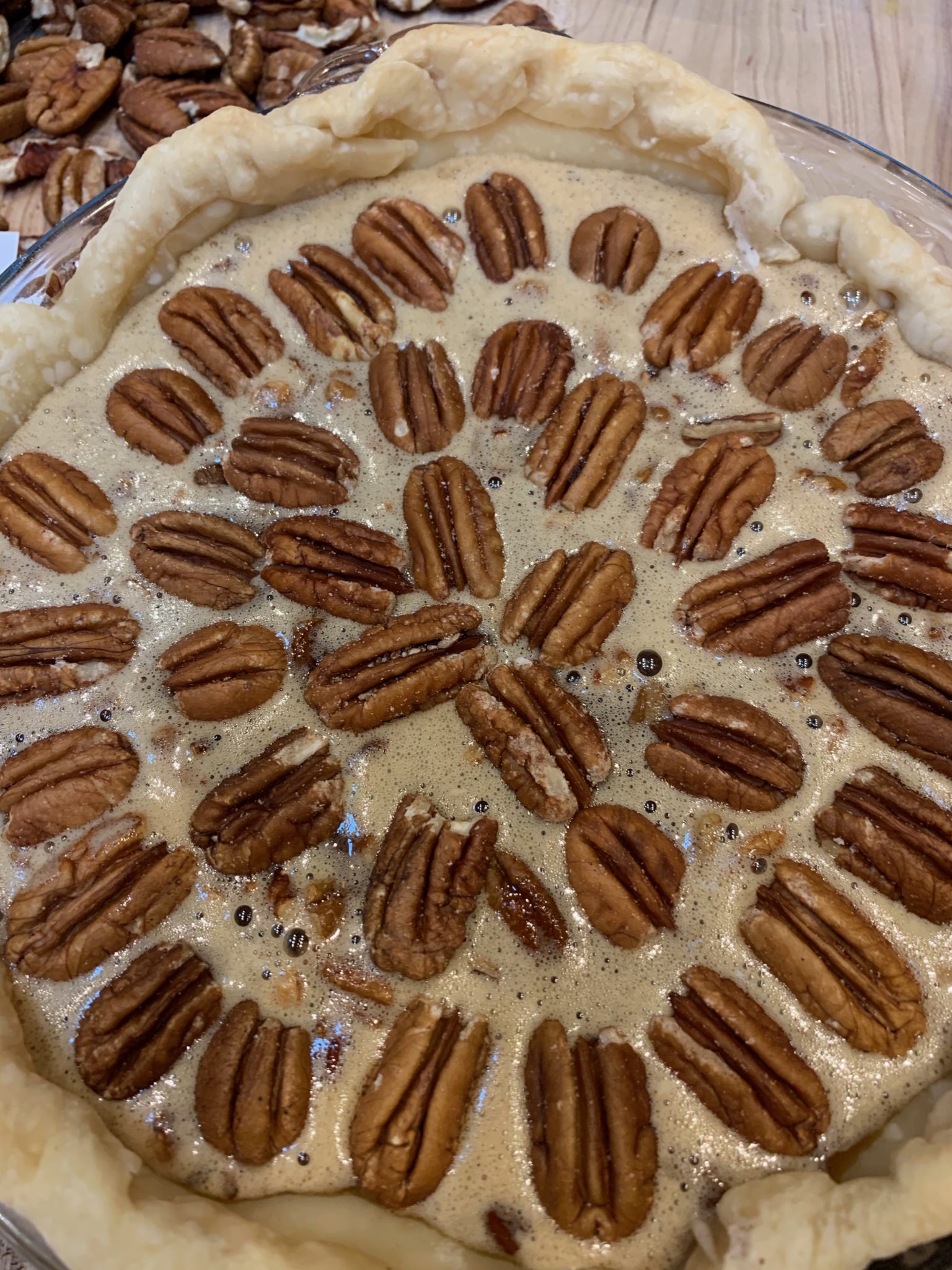 Showing a pecan pie decorated with pecan halves before baking