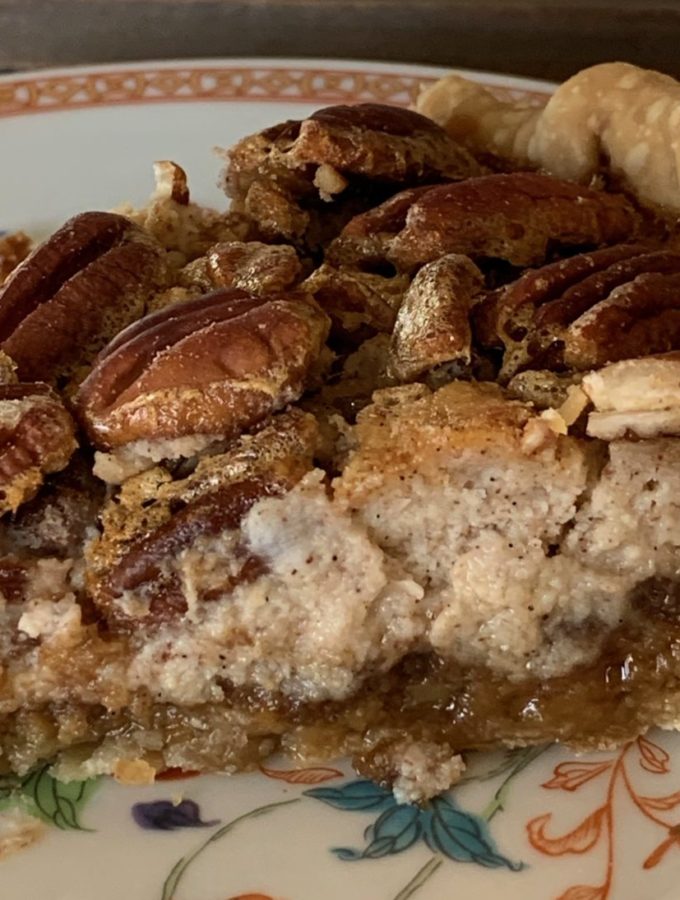 Showing the three layers of the layered pie: pecans, cheesecake and pecan pie filling