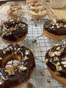 Chocolate Pecan donuts in front of Maple Glazed Bacon Donuts