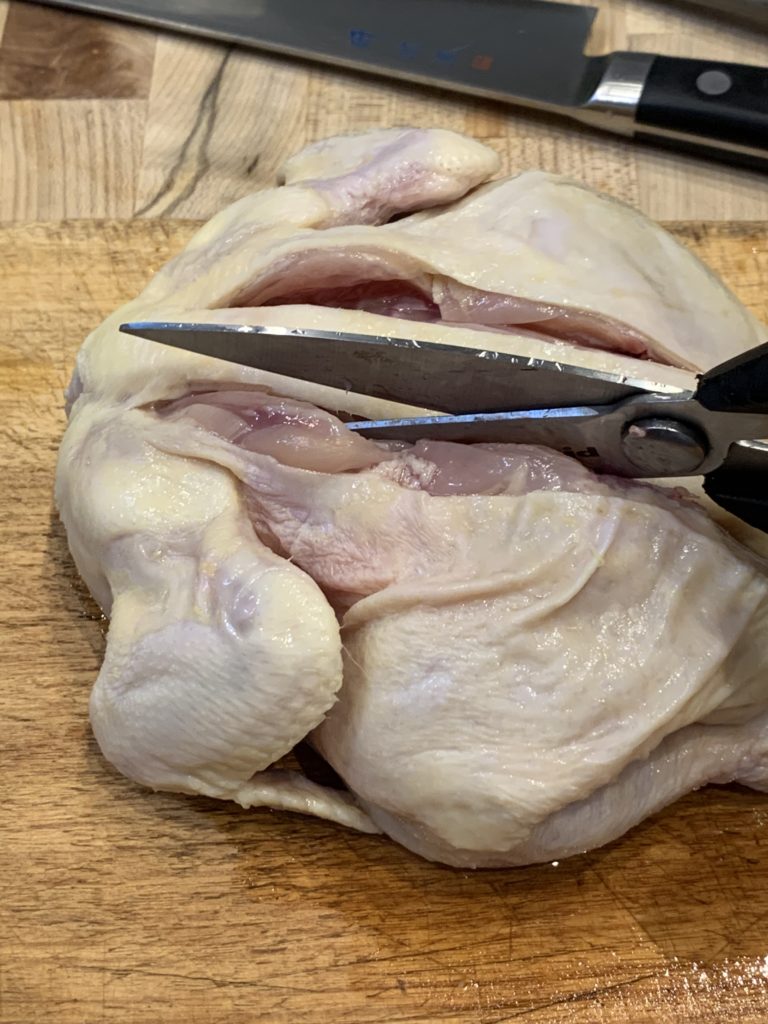Using kitchen shears to remove the backbone of a game hen