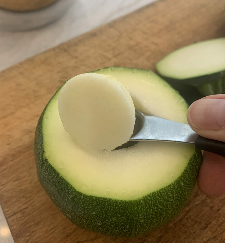 Scooping out the flesh of a round zucchini